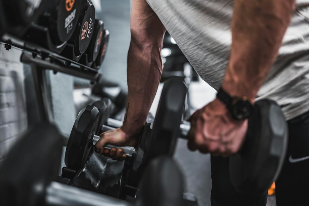 Beginner lifting dumbbells in a bright home workout space beside a notebook and water bottle.