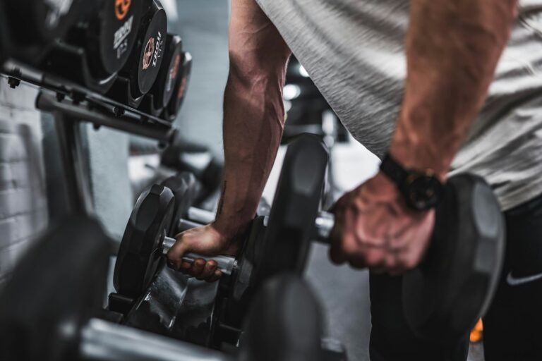 Beginner lifting dumbbells in a bright home workout space beside a notebook and water bottle.